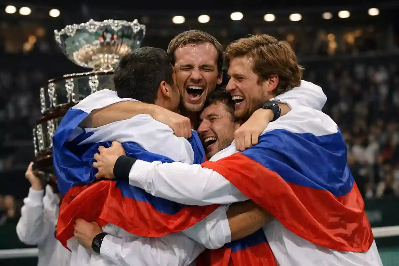 Equipo nacional de tenis celebrando una victoria en la Copa Davis con la bandera